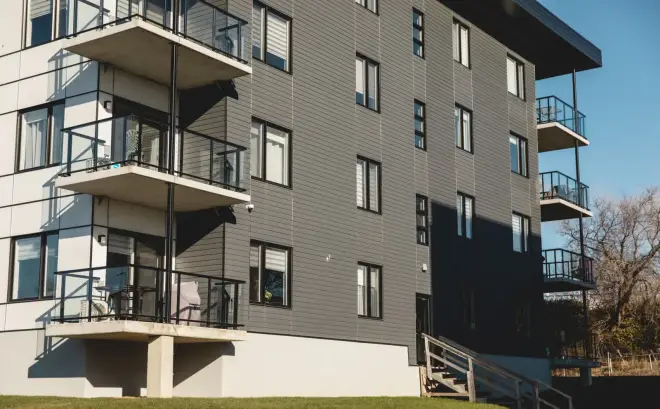 Immeuble à logements de quatre étages, balcons de béton en porte-à-faux sur toute la hauteur.